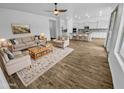 Bright, open living room showcases hardwood floors and a seamless transition into a modern, white kitchen at 12858 W Pasaro Dr, Peoria, AZ 85383