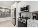 Modern kitchen featuring stainless steel appliances, white cabinets, and a neutral backsplash at 14950 W Mountain View Blvd # 5308, Surprise, AZ 85374