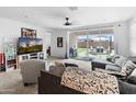 Bright living room featuring a ceiling fan, comfortable seating, and sliding glass doors to the backyard at 17055 W El Caminito Dr, Waddell, AZ 85355