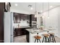 Modern kitchen with dark cabinets, stainless steel appliances, and a granite-topped island with seating at 20524 W Nelson Pl, Buckeye, AZ 85396