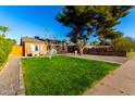 Well-maintained front yard with a green lawn, mature trees, and gravel landscaping surrounding a classic brick home at 2201 N 17Th Ave, Phoenix, AZ 85007