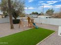 A backyard featuring desert landscaping, palm trees, and a playset at 2205 W Cambridge Ave, Phoenix, AZ 85009