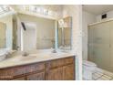 Bathroom with double sink vanity, patterned wallpaper, and a glass-enclosed shower at 4312 W Paradise Dr, Glendale, AZ 85304