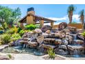 Spectacular backyard water feature with rock waterfall cascading into a serene pool, perfect for relaxation at 10597 E Rising Sun Dr, Scottsdale, AZ 85262