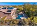 An eye-level shot of a luxurious pool with a rock-style waterfall feature in a home surrounded by desert landscaping at 11415 E Four Peaks Rd, Scottsdale, AZ 85262