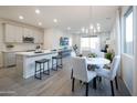 Open-concept living space with modern light fixture, grey wood floors, and an island with seating at 14598 W Wood Dr, Surprise, AZ 85379