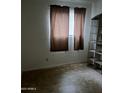 A simple bedroom with tiled floors, white walls and a window with brown curtains at 2605 W Rose Ln # B101, Phoenix, AZ 85017
