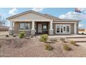 Charming single-story home featuring a covered front porch with stone accents and professionally landscaped yard at 26388 N 77Th Dr, Peoria, AZ 85383