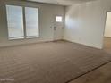 Bright living room with neutral carpet, white walls, and multiple windows offering ample natural light at 8965 N Sayonara Trl, Florence, AZ 85132