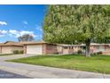 Attractive home featuring brick accents, a spacious lawn, and a large mature tree at 9606 W Shasta Dr, Sun City, AZ 85351
