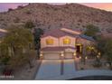 Beautiful two-story home with three-car garage and desert landscaping at sunset at 9867 S 182Nd Dr, Goodyear, AZ 85338