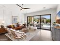 Bright living room with a leather couch, white chairs, and sliding glass doors to the backyard at 9921 E South Bend Dr, Scottsdale, AZ 85255