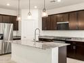 Modern kitchen featuring dark wood cabinets, granite countertops, and stainless steel appliances at 36986 W Prado St, Maricopa, AZ 85138