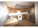 Traditional kitchen with wood cabinets, tiled floor, and stainless steel refrigerator at 4409 E Wood St, Phoenix, AZ 85040