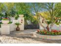 Grand entrance gate framed by lush landscaping and stone pillars, creating a welcoming approach to the property at 4900 E Desert Fairways Dr, Paradise Valley, AZ 85253