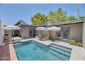 Backyard pool with tile accents, outdoor lounge seating, umbrellas, and modern patio at 6649 N Majorca E Ln, Phoenix, AZ 85016