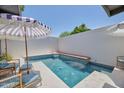Private pool area with modern tile, built-in seating, sun umbrellas, and blue water at 6649 N Majorca E Ln, Phoenix, AZ 85016