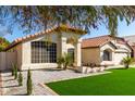 Charming single-story home showcasing gravel landscaping, a red tile roof, and a well maintained lawn at 7849 W Kristal Way, Glendale, AZ 85308