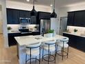 Modern kitchen with a large island, stainless steel appliances, and black cabinetry at 9965 W Flower St, Avondale, AZ 85392