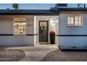 Inviting front entrance featuring a wreath-adorned door, potted flowers, and updated exterior lighting at 1011 E Cavalier Dr, Phoenix, AZ 85014