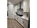 Modern kitchen featuring white cabinetry, subway tile backsplash, stainless steel range hood, and wood-look flooring at 13342 W Lariat Ln, Peoria, AZ 85383