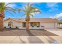 Charming single-story home featuring a two-car garage, desert landscaping, and beautiful palm trees at 13747 W Tartan Dr, Sun City West, AZ 85375