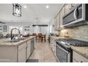 Open kitchen with stainless steel appliances, granite counters, tile floors, and view of the dining room at 16813 W Hammond St, Goodyear, AZ 85338