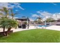 Landscaped backyard featuring a gazebo, lounge chairs, and artificial turf surrounding a refreshing pool at 19349 W Oregon Ave, Litchfield Park, AZ 85340