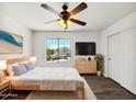 Comfortable bedroom with modern decor, ceiling fan, wood floors, and a bright window view at 19603 N Toya St, Maricopa, AZ 85138