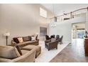 A spacious living room with high ceilings and a staircase leading to a second-floor landing above dining area at 21798 N Ingram Ct, Maricopa, AZ 85138