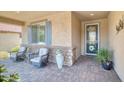 Inviting covered porch with comfortable seating, stone accents, and a decorative front door enhancing curb appeal at 26578 W Piute Ave, Buckeye, AZ 85396