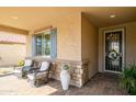 Inviting front porch with two chairs, decorative window shutters, and a decorative storm door at 26578 W Piute Ave, Buckeye, AZ 85396