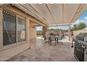 Inviting outdoor patio area featuring a pergola, dining set, and grill, ideal for outdoor dining and relaxation at 30480 N 128Th Ln, Peoria, AZ 85383