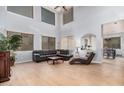 Bright living room with high ceilings, hardwood floors, and a comfortable black leather sectional at 38274 N Tumbleweed Ln, San Tan Valley, AZ 85140