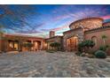 Stunning Tuscan-style home with a stone facade, arched entryway, and a meticulously paved circular driveway at 42613 N 111Th Pl, Scottsdale, AZ 85262