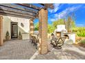 Relaxing outdoor patio featuring a pergola, an outdoor fireplace, grill, comfortable seating, and a neatly paved floor at 6611 E Peak View Rd, Cave Creek, AZ 85331