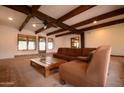 Spacious living room featuring exposed wood beams, a large sectional sofa, and natural light from windows at 9620 S 156Th Pl, Gilbert, AZ 85234