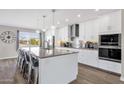 Bright kitchen featuring white cabinetry, stainless steel appliances, a granite island and pendant lighting at 12806 W Jadestone Dr, Sun City West, AZ 85375