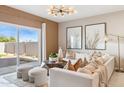 Bright living room with neutral tones, modern chandelier, and sliding glass doors to the outdoor space at 1531 S 239Th Dr, Buckeye, AZ 85326