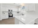 Bright, white kitchen with stainless steel appliances, stone countertops and a view from the arched window at 2502 S 90Th Gln, Tolleson, AZ 85353