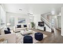 Bright living room features a white couch, plush rug, staircase, and ample natural light at 2502 S 90Th Gln, Tolleson, AZ 85353