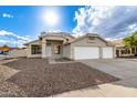 Charming beige home featuring a three-car garage, low-maintenance landscaping and concrete driveway at 5145 W Tonto Rd, Glendale, AZ 85308