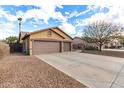 Spacious three-car garage with a long driveway and desert landscaping in the front yard at 545 N Bluejay Dr, Gilbert, AZ 85234