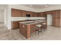 Well-equipped kitchen featuring a central island with seating, dark wood cabinets and tile flooring at 742 E Watermelon Ln, Queen Creek, AZ 85140