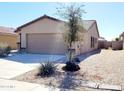 A single-story home with a tile roof, desert landscaping, and a two car garage on a sunny day at 1061 W Palo Verde Ave, Coolidge, AZ 85128