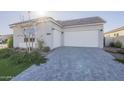 Modern home features a two-car garage and stylish paver driveway, set against a sunny sky at 10972 N Hershey St, Surprise, AZ 85388