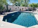 Sparkling blue pool with a waterfall feature, surrounded by desert landscaping and a decorative privacy wall at 11122 N 165Th Ave, Surprise, AZ 85388