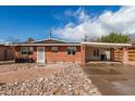 Inviting single-story brick home with a covered carport and distinctive rock landscape design in the front yard at 1512 W Fairmont Dr, Tempe, AZ 85282