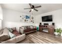 Cozy living room features wood-look floors, comfortable sofas, ceiling fan, and stylish decor on the accent wall at 1512 W Fairmont Dr, Tempe, AZ 85282