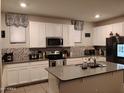 Bright kitchen with white cabinetry, mosaic backsplash, stainless steel appliances, and a central island at 16648 W Jenan Dr, Surprise, AZ 85388